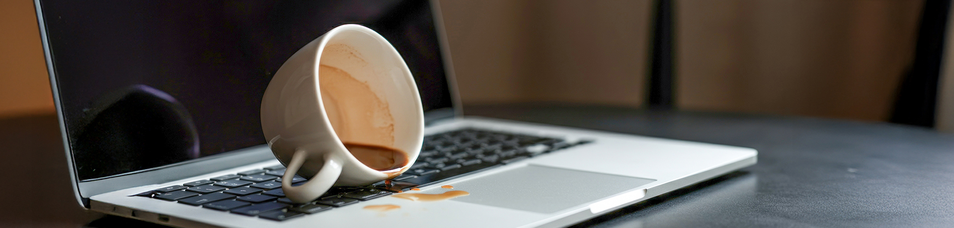 Umgekippte Kaffeetasse auf einem Laptop