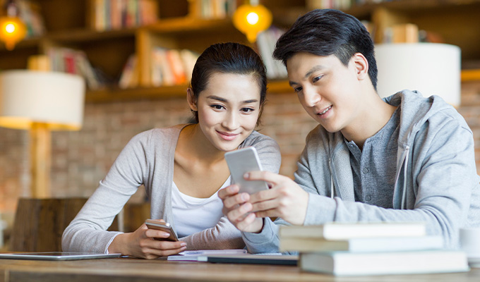 Zwei Student*innen schauen gemeinsam in ein Smartphone