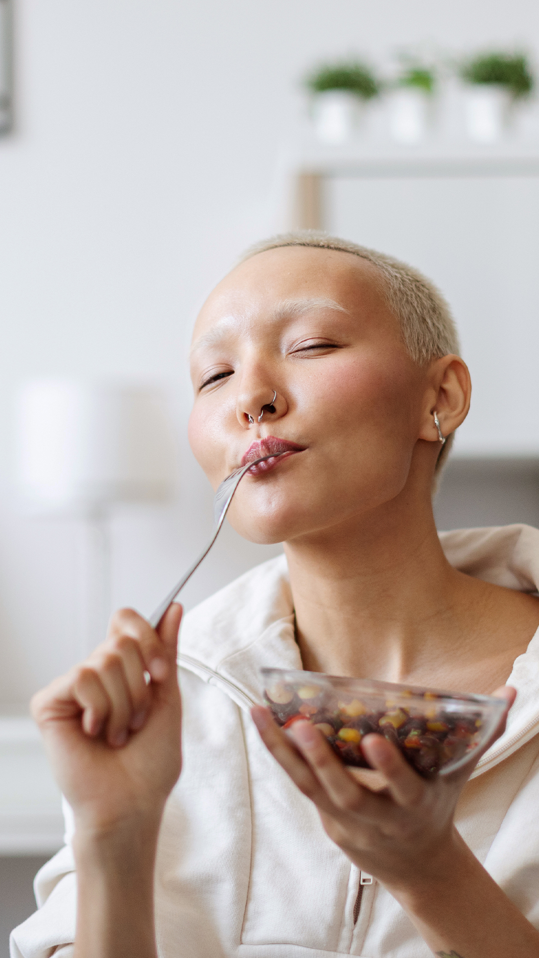 Eine Studentin sitzt in ihrer Küche und genießt ihr Essen.